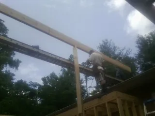 Carpenter setting a ridge beam over a new addition frame — Ice Dam Removal by Roofing Brothers in West Yarmouth