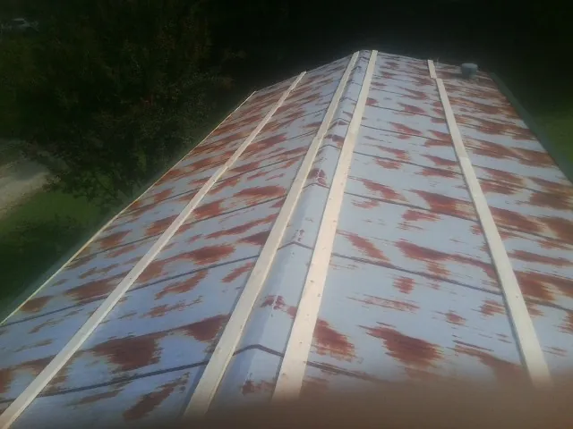 Rusted metal roof panels with new wood purlins before replacement — Storm Damage Roof Repair in West Yarmouth by Roofing Brothers