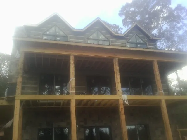 Dormers and porch framing on a large log home under construction — Roof Coating work by our crew in West Yarmouth