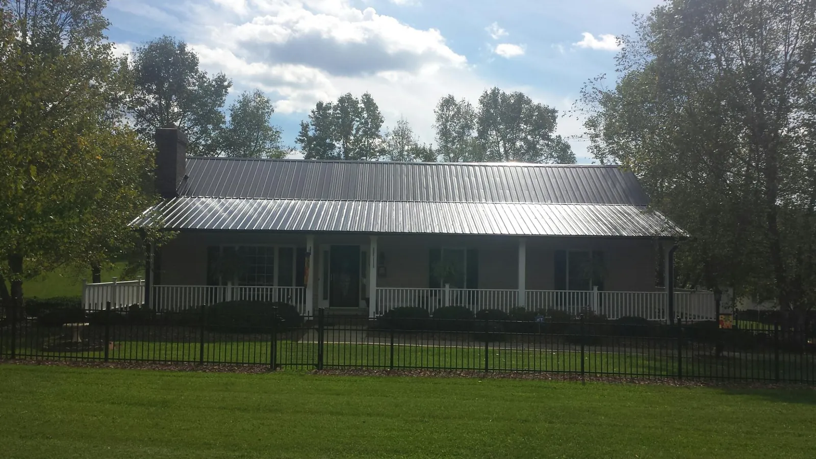 Gray metal roof on a brick ranch with a full width front porch — Gutter Guard Installation work by our crew in West Yarmouth