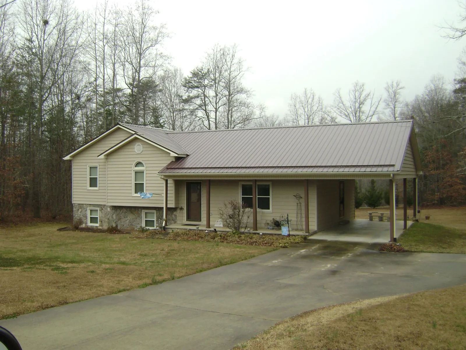 Brown metal roof on a tan split level home with an attached carport in West Yarmouth