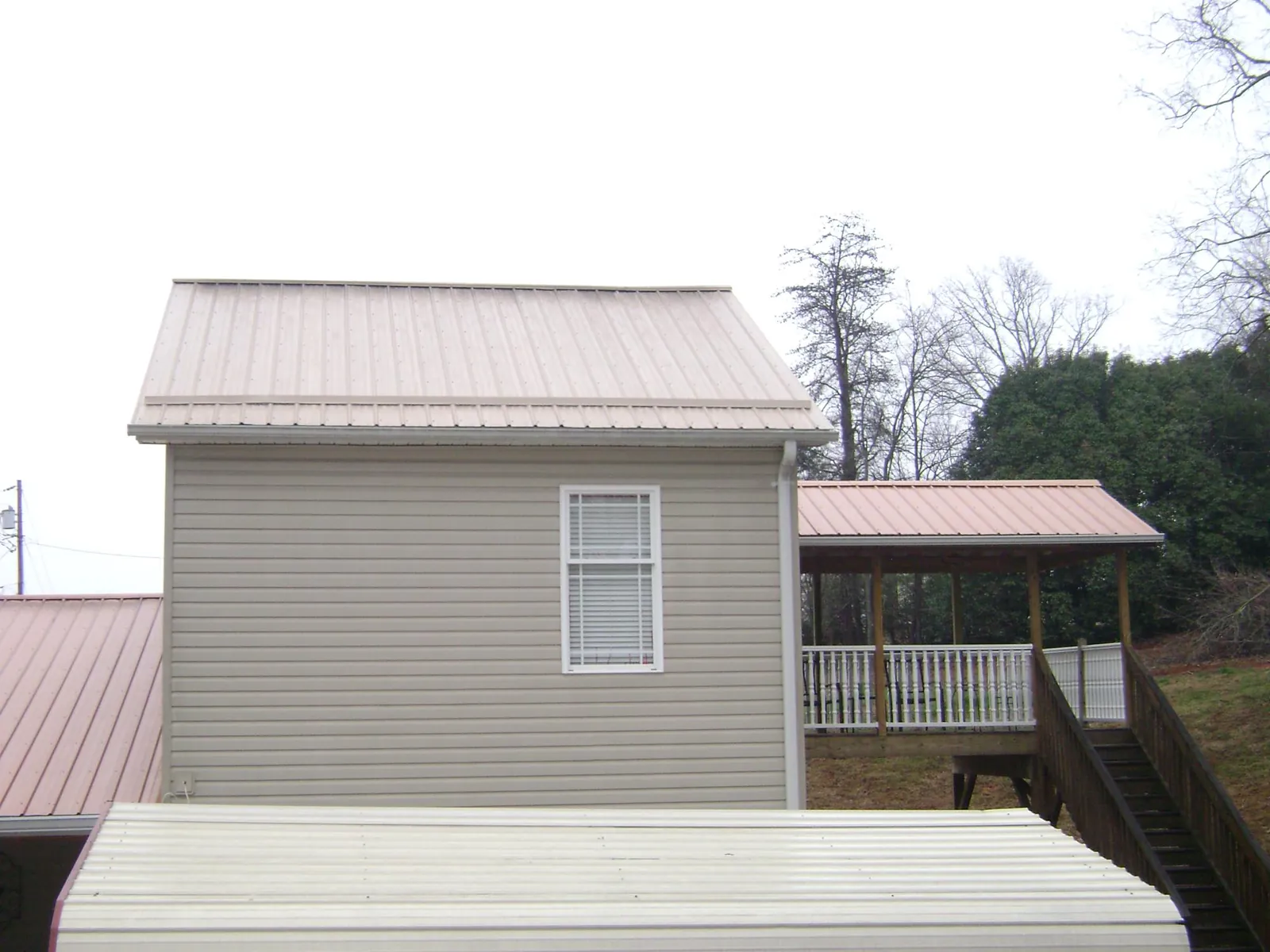 Tan metal roofs on a two story addition and attached porch, from a Roof Replacement job in West Yarmouth