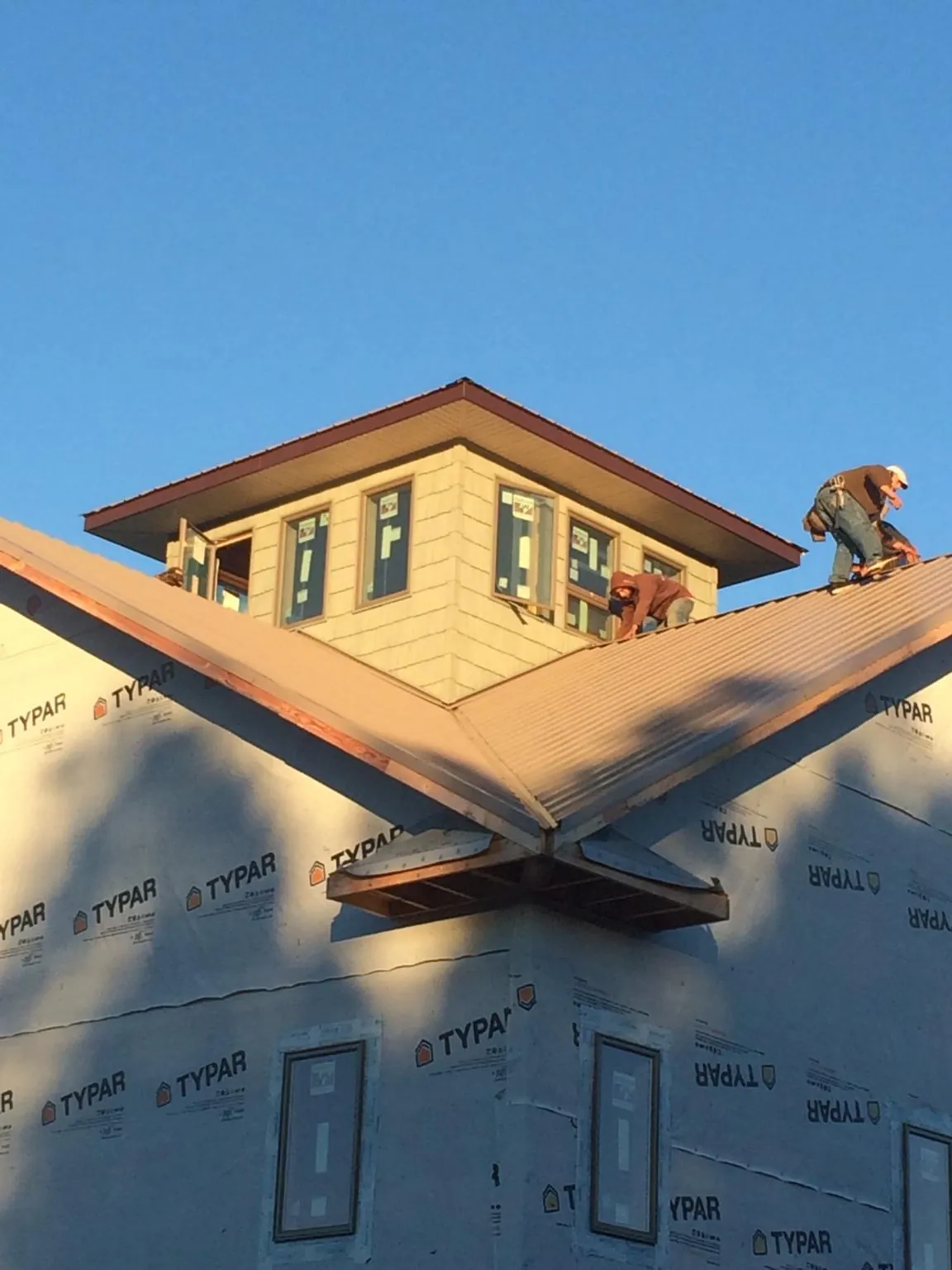 Roofers working around a rooftop cupola on a new metal roof at sunset — Roof Waterproofing in West Yarmouth by Roofing Brothers